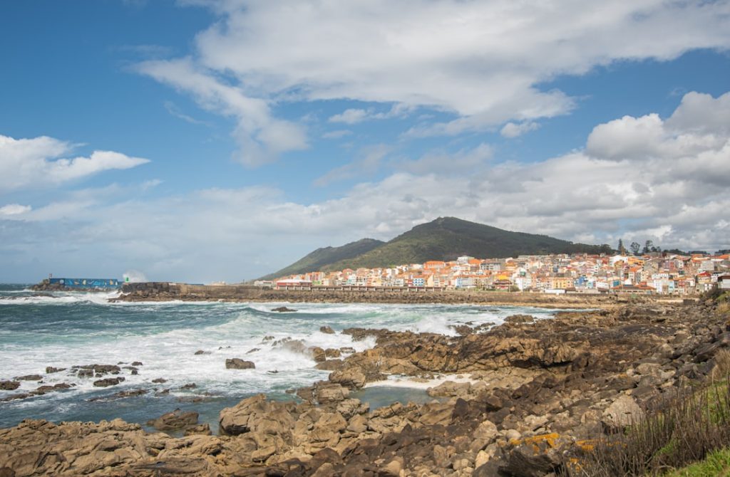 Waves crash onto a rocky shore near a town.